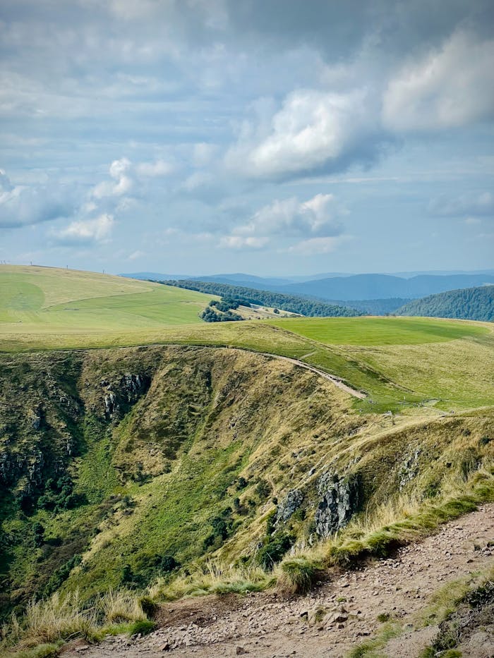 Explore a breathtaking mountain view with lush greenery and dramatic cliffs under a cloudy sky.